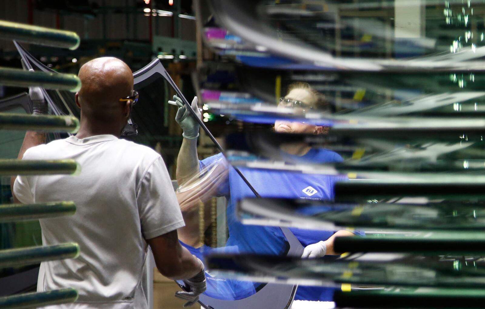 Workers at Fuyao Glass America finish an automobile windshield in the Moraine plant.  Fuyao currently employs 2,300 workers and expects to need 700 more in 2019.   TY GREENLEES / STAFF