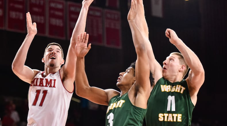 Miami’s Logan McLane (11), left, drives to the hoop defended by Wright State’s Mark Hughes (3) and Loudon Love (11) during their game Tuesday, Nov. 14 at Millett Hall on the Miami University Campus in Oxford. NICK GRAHAM/STAFF