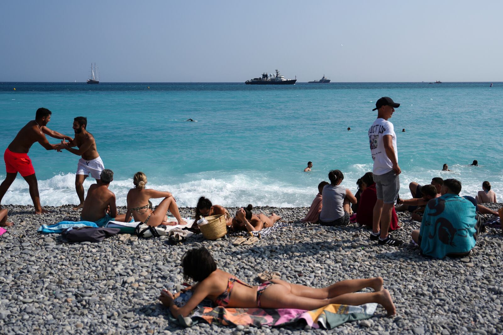 People enjoy the beach as vessels sail during the "Ocean Wonders" event in honor of World Oceans Day ahead of the U.N. Ocean Conference on Sunday, June 8, 2025, in Nice, France. (AP Photo/Annika Hammerschlag)