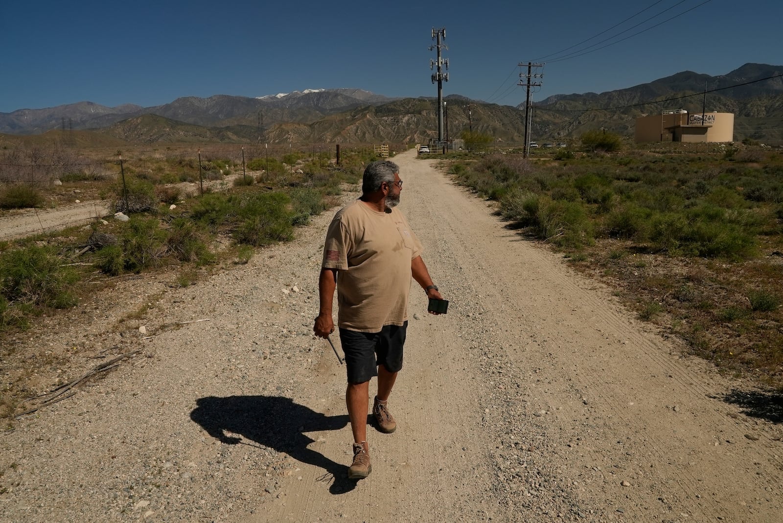 Glenn Chavez sets the distance for which a helicopter pilot can remotely turn on a Heli-Hydrant, a small, open tank that helicopters can rely on to get water faster for urban fires, Friday, April 11, 2025, in Cabazon, Calif. (AP Photo/Brittany Peterson)