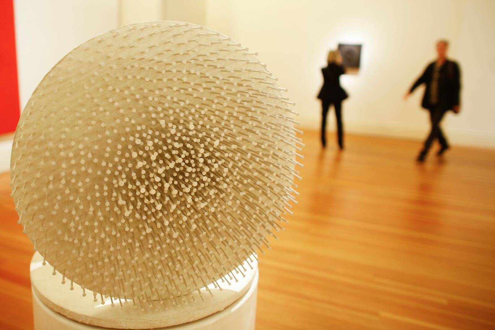 FILE - People walk behind the art work 'Weisse Muehle' ( White Mill), by artist Guenther Uecker during the press preview of the ZERO exhibition in Berlin, Friday, March 20, 2015. (AP Photo/Markus Schreiber, File)