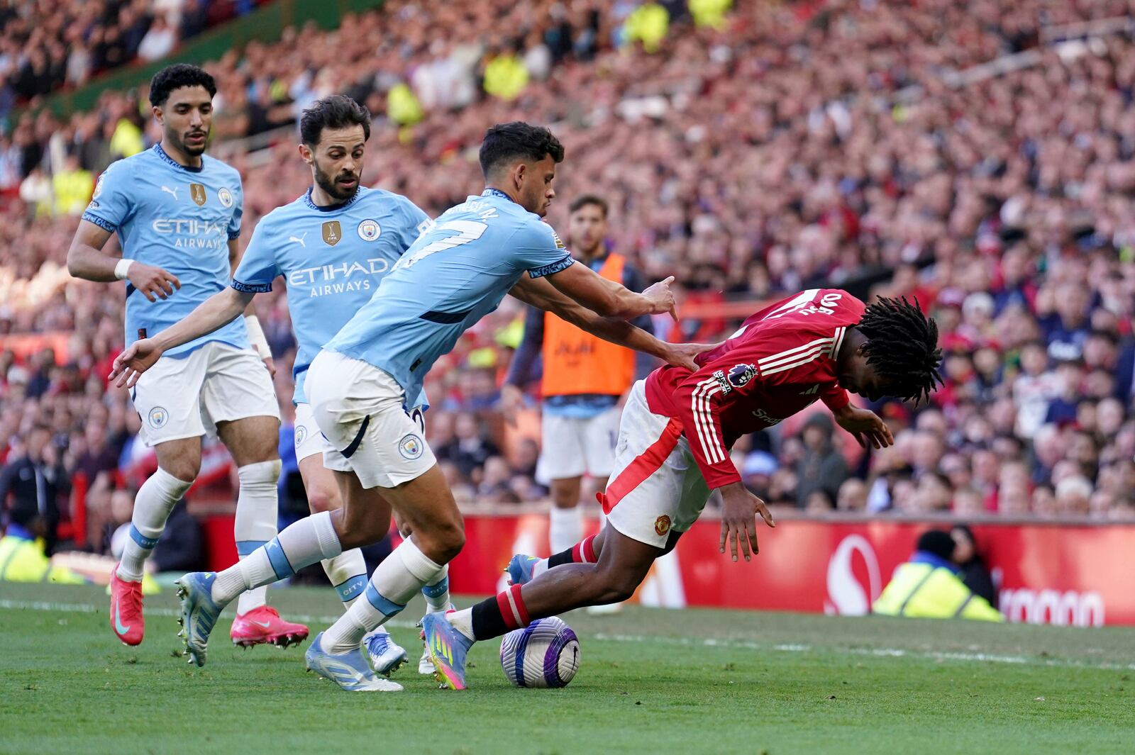 Manchester City's Matheus Nunes, left, and Manchester United's Patrick Dorgu, right, battle for the ball during the English Premier League soccer match between Manchester City and Manchester United in Manchester, England, Sunday, April 6, 2025. (Martin Rickett/PA via AP)