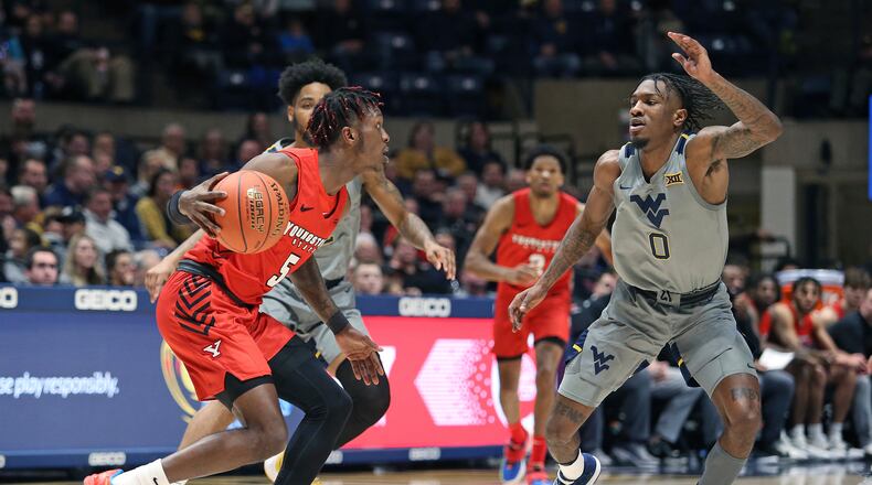 Youngstown State guard Dwayne Cohill (5) is defended by West Virginia guard Kedrian Johnson (0) and another player during the second half of an NCAA college basketball game in Morgantown, W.Va., Wednesday, Dec. 22, 2021. (AP Photo/Kathleen Batten)