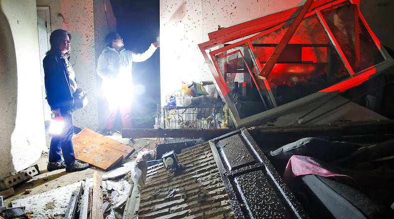 Emi Campbell, left, and her daughter, Emma, look over their destroyed home along Ridge Road Wednesday morning, Feb. 28, 2024 after it was struck by a tornado with them in it. BILL LACKEY/STAFF