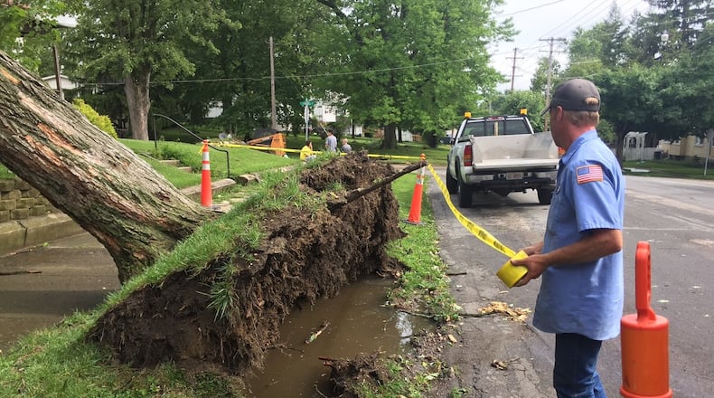 Utility crews used caution tape to rope off a section of sidewalk on S. Maple in Eaton were a tree was uprooted during a storm Tuesday afternoon that brought rough winds and heavy rain through the region. KATE BARTLEY/STAFF