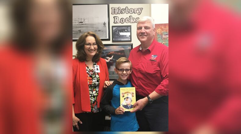East Dayton Christian School history teacher Sue Norrod, student EZ Morse and his grandfather and founder of Honor Flight, Earl Morse, on Oct. 7 with the book that surprised EZ and brought “Pappy” to his school. CONTRIBUTED