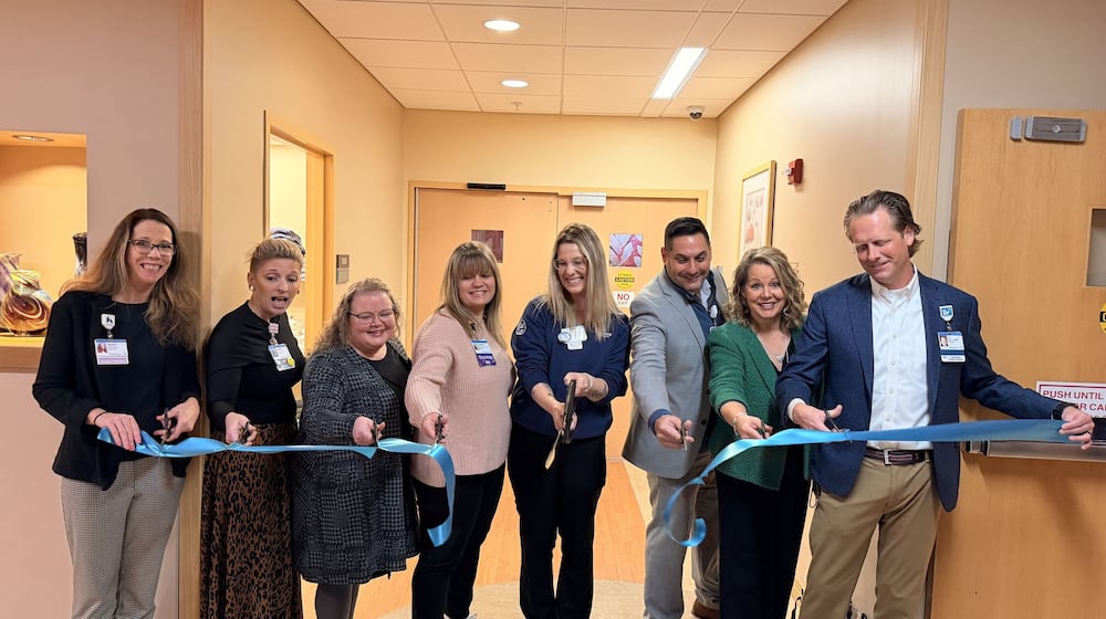 Jessica Schwab (center), an oncology radiologist at Kettering Health, cuts the ribbon during a ceremony marking the opening of Coats for a Cure's second Care Closet at Soin Medical Center, with the first one located at Kettering Health Main Campus. Schwab, along with Zach Gregus and Crystal Bullock, both oncology radiologists at Kettering Health, founded Coats for a Cure and partnered with Kettering Health after they noticed many patients were coming in for medical appointments without proper winter clothing. CONTRIBUTED