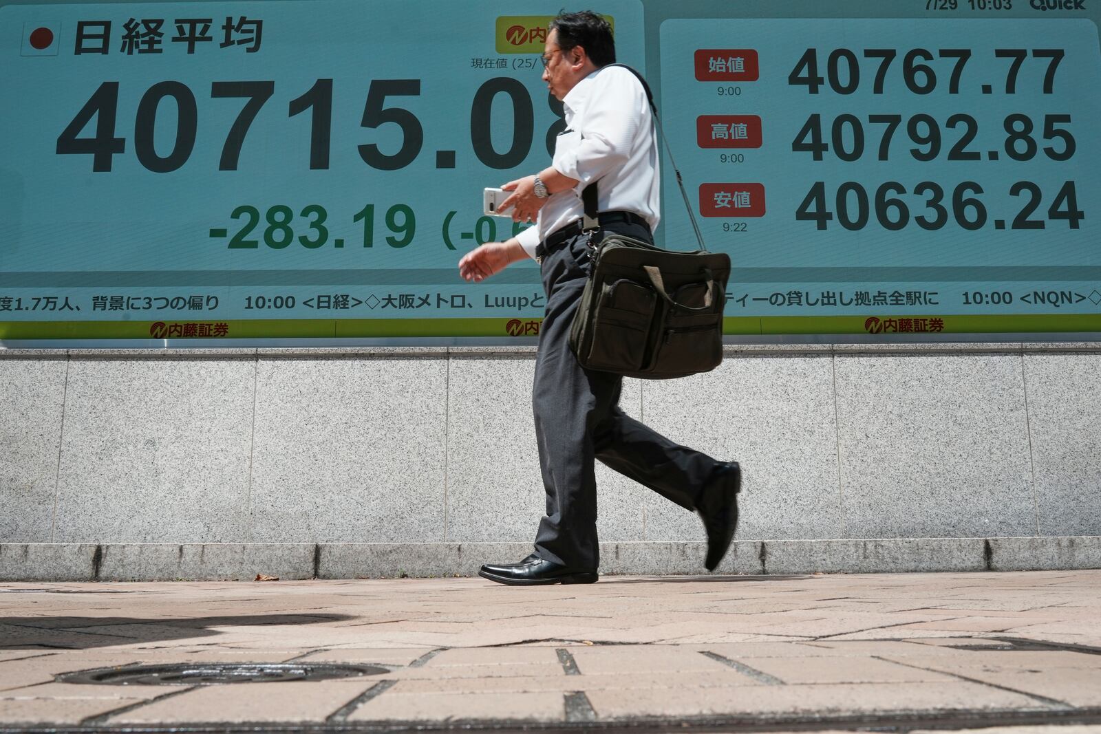 A person walks in front of an electronic stock board showing Japan's Nikkei index at a securities firm Tuesday, July 29, 2025, in Tokyo. (AP Photo/Eugene Hoshiko)