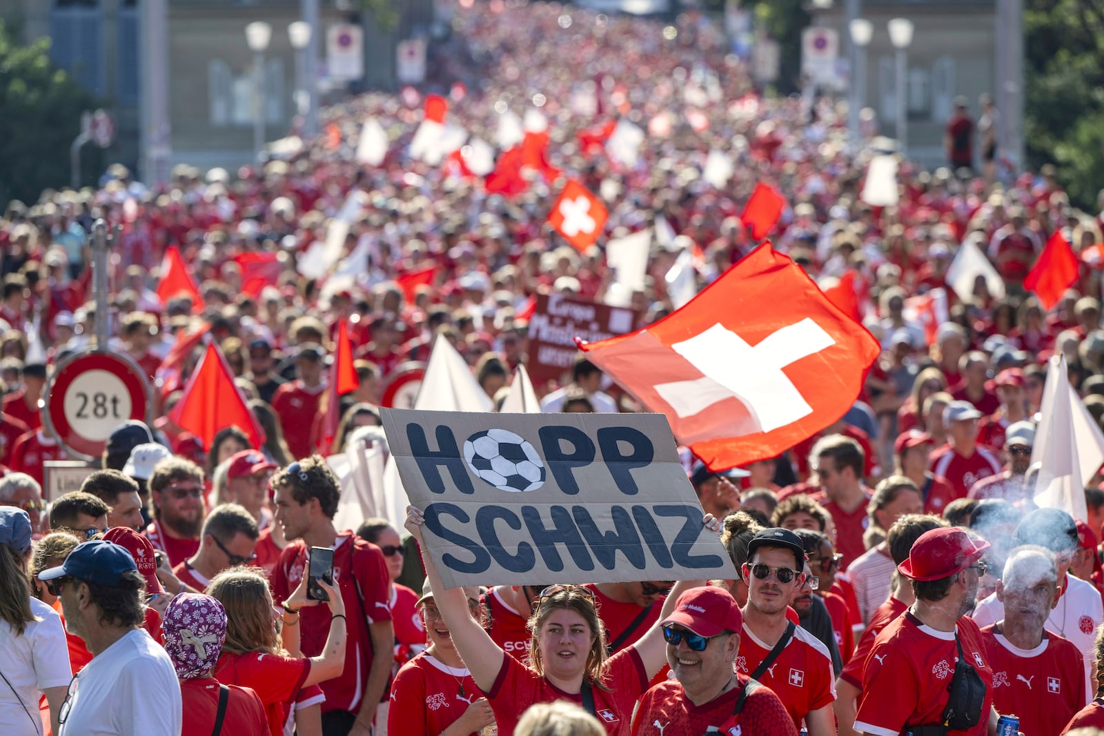 A fan holds a poster with the words in German "Go Switzerland" while walking with thousands to the stadium for he Women's Euro 2025 quarterfinal soccer match between Switzerland and Spain in Bern, Switzerland, Friday July 18, 2025. (Urs Flueeler/Keystone via AP)