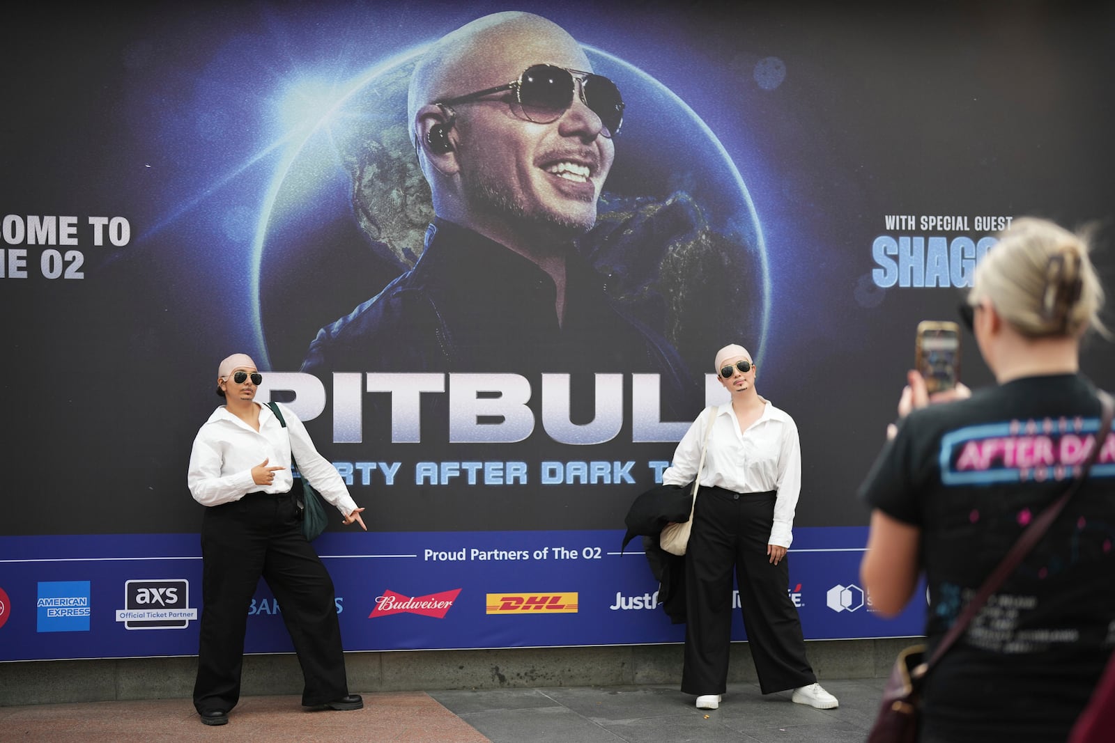 Fans pose for a photograph as they gather prior to a performance by Pitbull on Monday, June 9, 2025, in London. (Photo by Scott A Garfitt/Invision/AP)