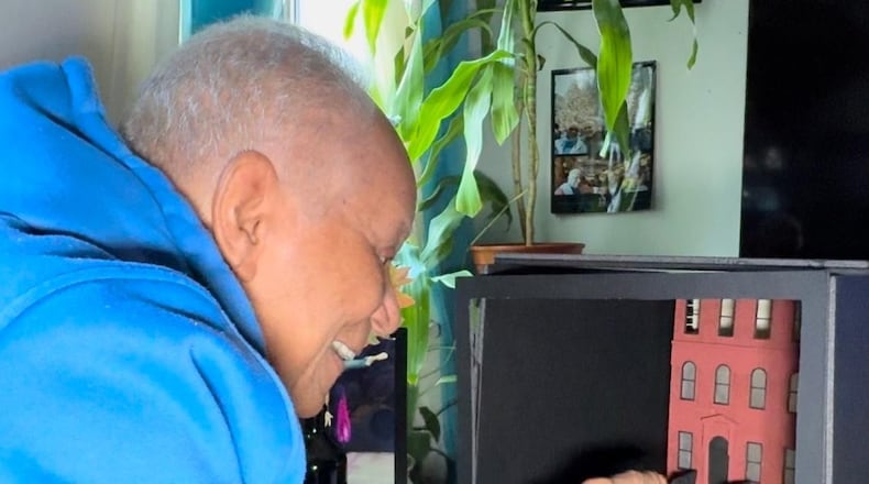 Broadway veteran Nat Norne, who served 18 years as director/choreographer of the Muse Machine musicals, points to his favorite stoop spot outside his “home” (in a theatrical maquette) in the Hell's Kitchen neighborhood of New York City. Photo courtesy of Benjamin Magnuson