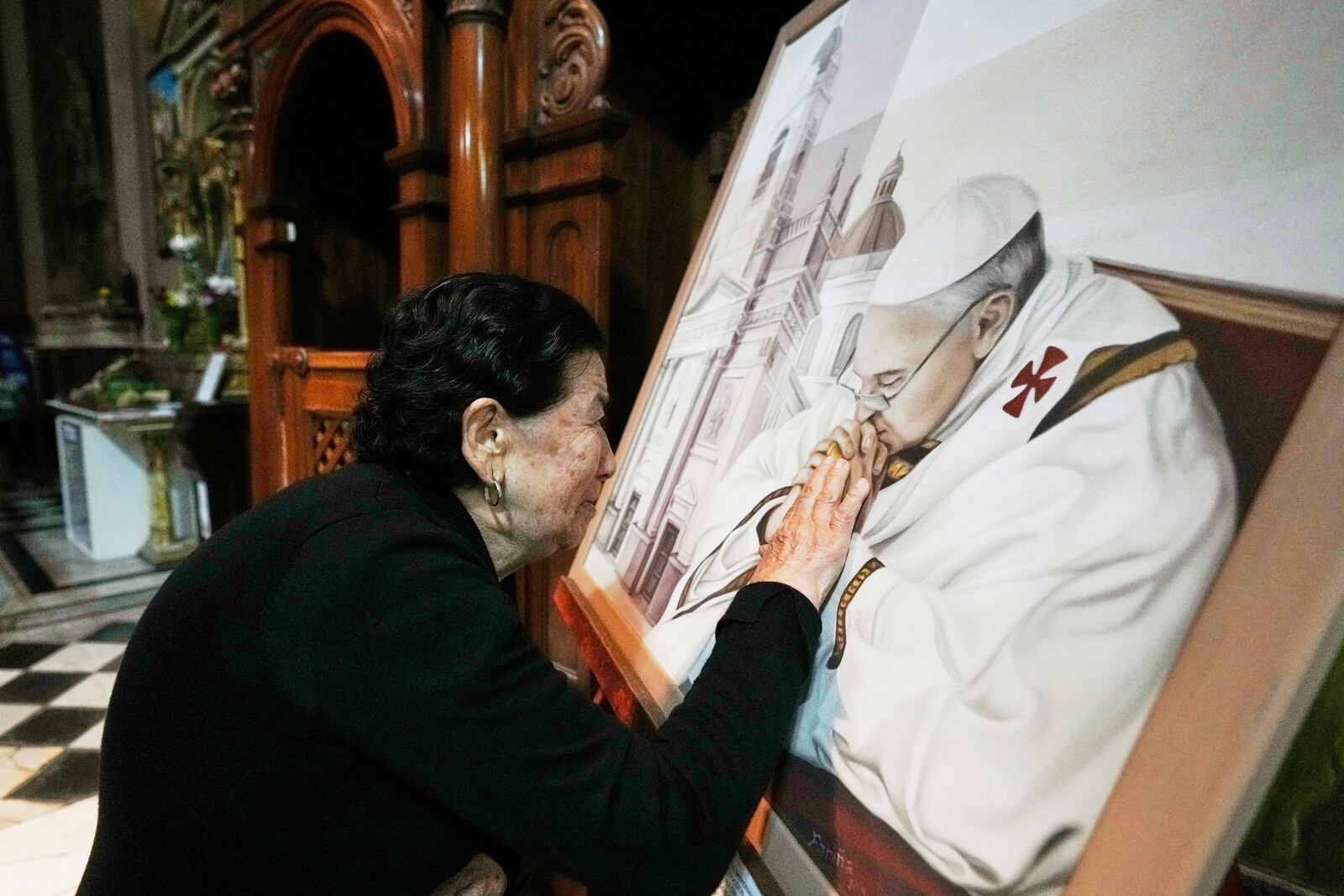 A parishioner touches a painting of the late Pope Francis at the Basílica de San José de Flores, where he worshipped as a youth, following the Vatican's announcement of his death in Buenos Aires, Argentina, Monday, April 21, 2025. (AP Photo/Gustavo Garello)