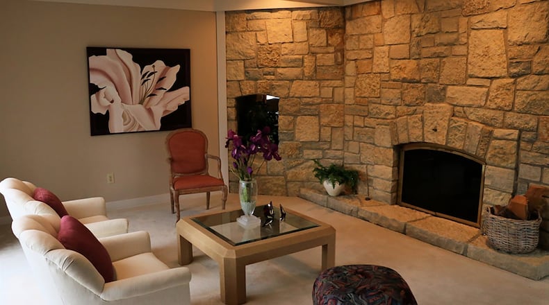 One step down from the opposite side of the foyer, the formal living room enjoys a stone fireplace placed on an angled wall and a grouping of tall casement windows in an alcove.