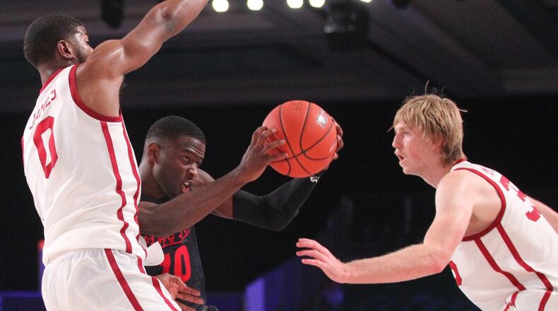 Dayton’s Jalen Crutcher drives against Oklahoma’s Christian James, left, and Brady Manek, right, on Friday, Nov. 23, 2018, in the third-place game of the Battle 4 Atlantis at Imperial Gym on Paradise Island, Bahamas. David Jablonski/Staff