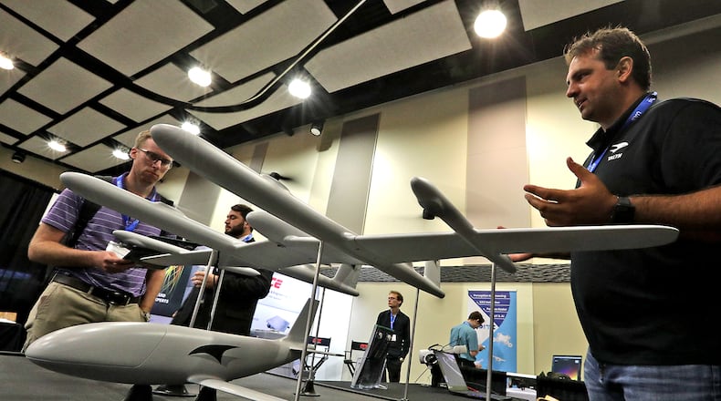 Jordan Thompson, right, from Talyn Air, talks with Alex Zorniger about the design of their craft Monday, August 22, 2022 during the National Advanced Air Mobility Industry Forum at Clark State's Hollenbeck-Bailey Conference Center in Springfield. BILL LACKEY/STAFF