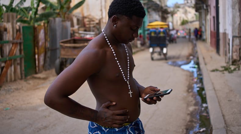 A man wearing a rosary looks at his phone during a blackout in Havana, Cuba, Thursday, March 5, 2026. (AP Photo/Ramon Espinosa)