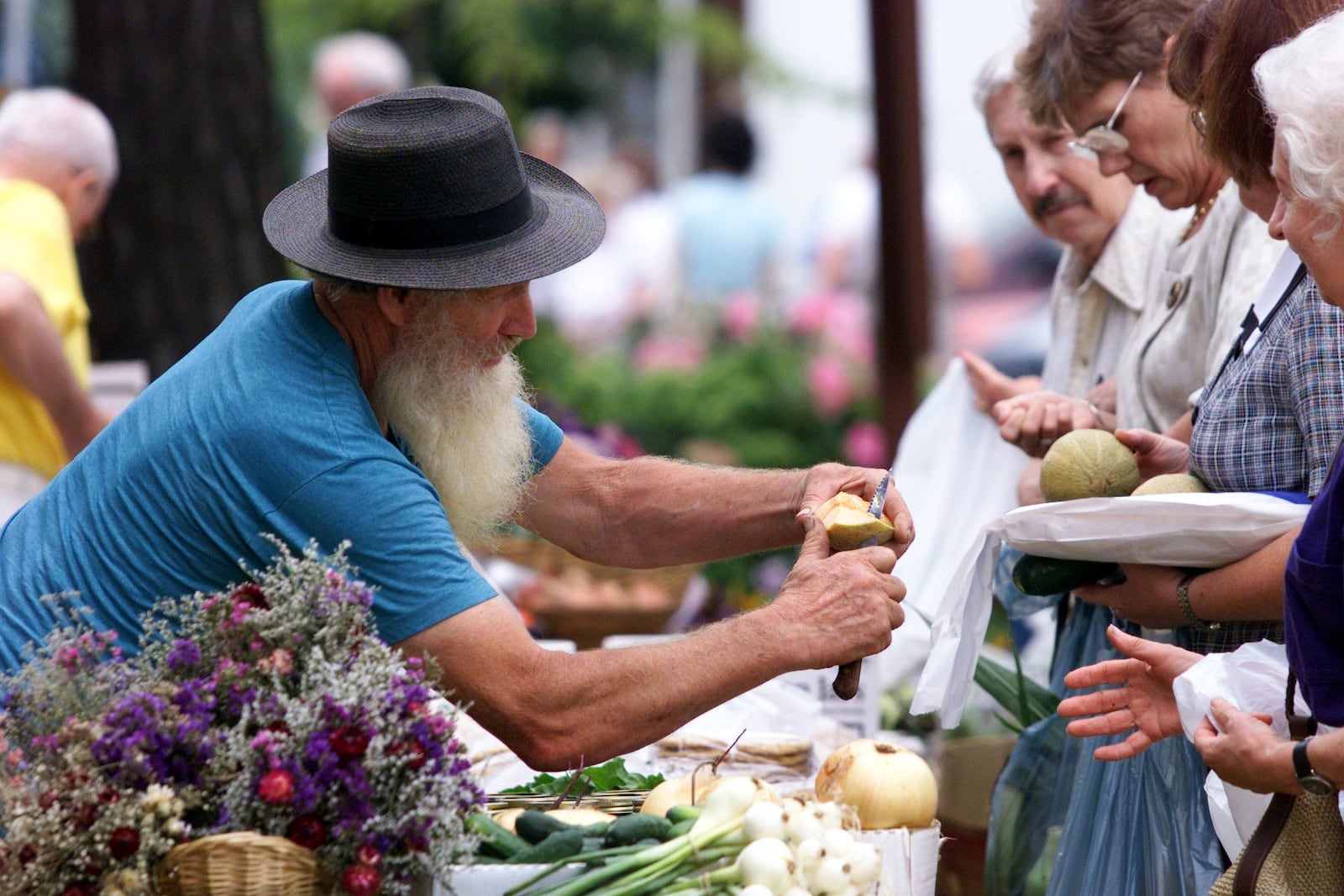 Russell Garber of Greenville, slices melon for customers at his stand at the Far Hills Farmer's Market in 2000. DAYTON DAILY NEWS ARCHIVES