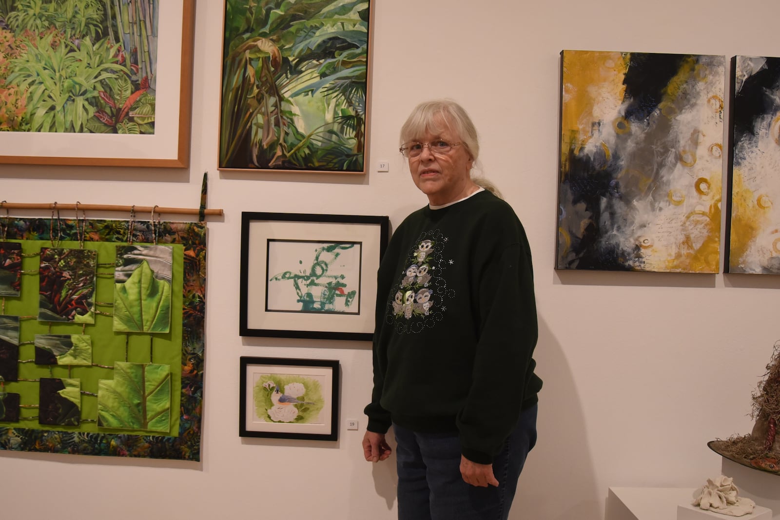 Just a few weeks away from her 72nd birthday, Cathy Jenkins poses next to a painting of birds she created, pictured closest to the bottom, at the Springfield Museum of Art’s McGregor Gallery as part of the museum's 79th Juried Members’ Exhibition during a showcase on Nov. 6, 2025. CONTRIBUTED