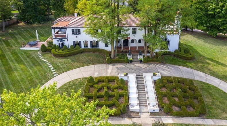 This stately Mediterranean-style home, designed by Louis Lott, sits on a 1-acre lot in Oakwood. Built in 1928, the stucco two-story with a terra-cotta tile roof has terrace porches, arched entries, courtyard parking and wrought-iron accents. The home is highlighted by a maze of boxwood gardens surrounding cascading waterfalls that flank a staircase to the circular driveway. Listed for $899,900 by Jill Aldineh of RE/MAX Victory, the home at 555 Rubicon Road in Oakwood has about 5,600 square feet of living space. To see other homes listed, visit DaytonDailyNews.com/homes. PHOTOS COURTESY OF DAYTON REALTORS.
