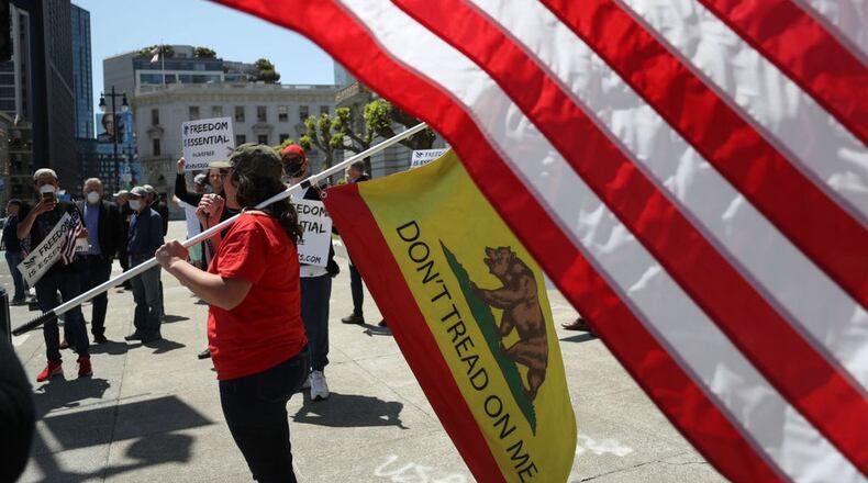 SAN FRANCISCO, CALIFORNIA - MAY 01: A demonstrator holds a custom 'Don't Tread On Me' flag as she protests California Gov. Gavin Newsom's continued statewide shelter in place order outside of San Francisco City Hall on May 01, 2020 in San Francisco, California. Thousands of people rallied in cities throughout California to protest against California's shelter in place order due to the coronavirus (COVID-19) pandemic. (Photo by Justin Sullivan/Getty Images) (Justin Sullivan/Getty Images)