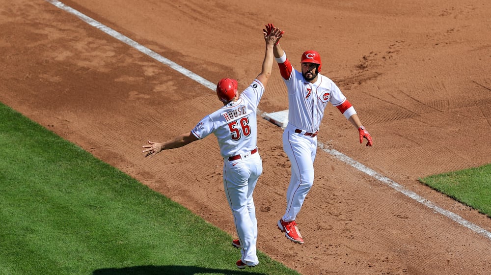 Cincinnati Reds' Eugenio Suarez, right, high-fives J.R. House after hitting a solo home run during the fourth inning of a baseball game against the Pittsburgh Pirates in Cincinnati, Monday, Sept. 27, 2021. (AP Photo/Aaron Doster)
