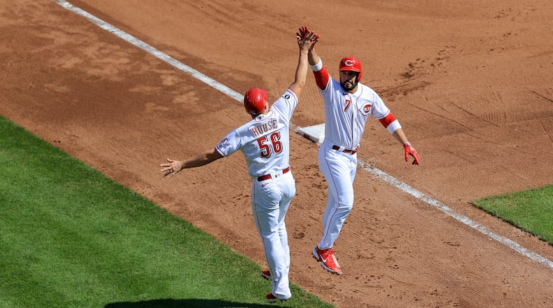 Cincinnati Reds' Eugenio Suarez, right, high-fives J.R. House after hitting a solo home run during the fourth inning of a baseball game against the Pittsburgh Pirates in Cincinnati, Monday, Sept. 27, 2021. (AP Photo/Aaron Doster)