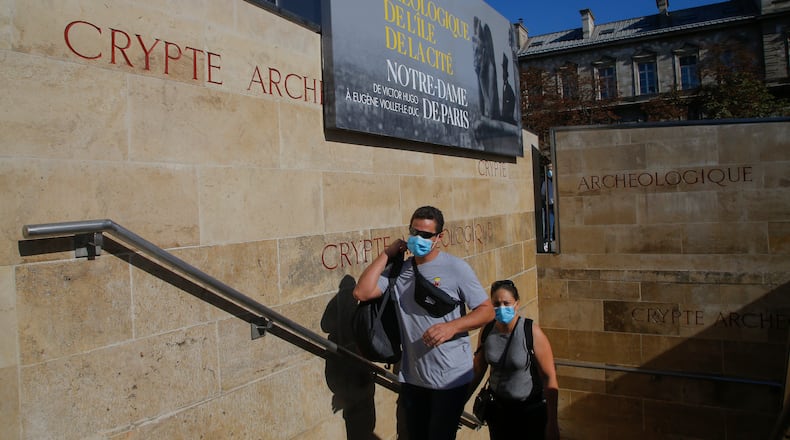 People wearing protective face masks as precaution against the conoravirus walk out of the archaeological crypt underneath the parvis of Notre-Dame cathedral which reopens today in in Paris, Wednesday, Sept. 9, 2020. The archaeological crypt was shut down after the cathedral caught fire in April 2019, and it returns with a exhibition called Notre-Dame de Paris from Victor Hugo to Eugene Viollet-le-Duc . (AP Photo/Michel Euler)