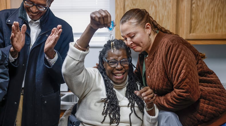 Gwendolyn Iheme, center, celebrates by holding a key to her new house that was given to her by Springfield Restore manager Rathena Austin, right, during a home dedication hosted by the Habitat for Humanity of Greater Dayton on Friday, Dec. 12, 2025, in Springfield. The ceremony was for Iheme, who will live in the house with her 8-year-old granddaughter Rileyanna Foster. JOSEPH COOKE/STAFF
