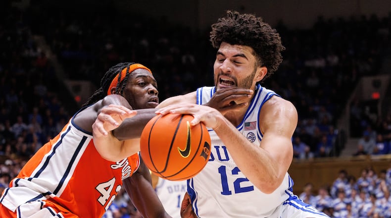 Duke's Cameron Boozer (12) handles the ball as Syracuse's William Kyle III, left, defends during the second half of an NCAA college basketball game in Durham, N.C., Monday, Feb. 16, 2026. (AP Photo/Ben McKeown)