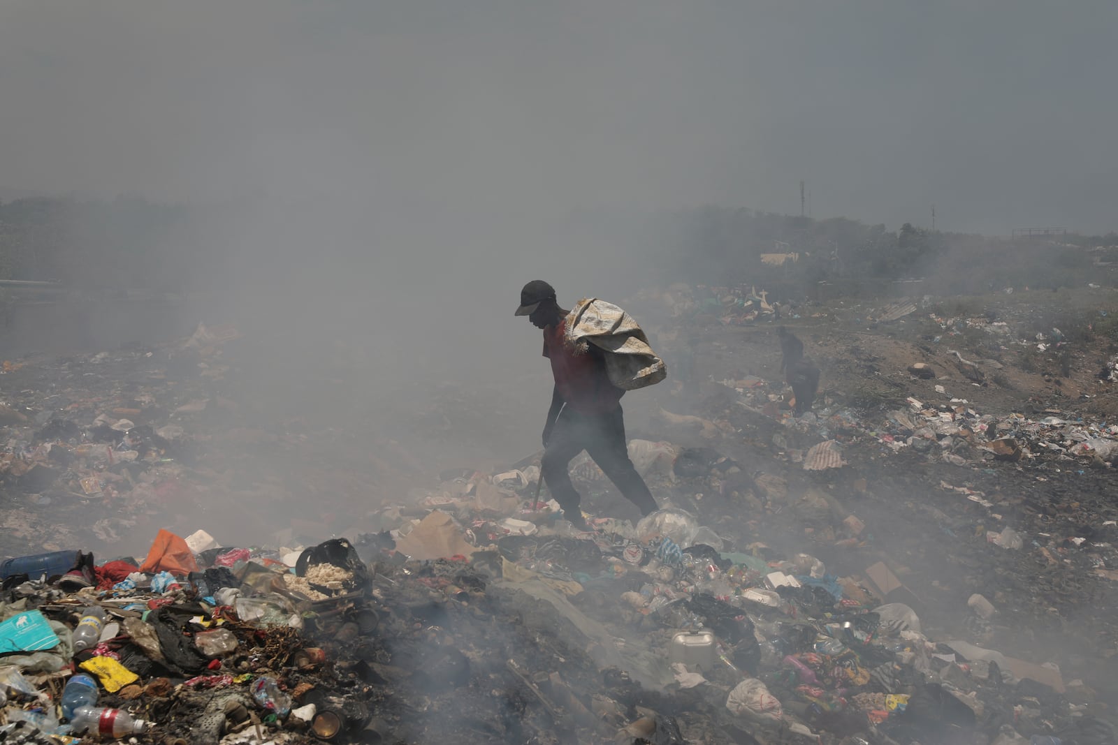 A man looks for useful items to use or sell, in a landfill in Port-au-Prince, Haiti, Friday, July 25, 2025.(AP Photo/Odelyn Joseph)