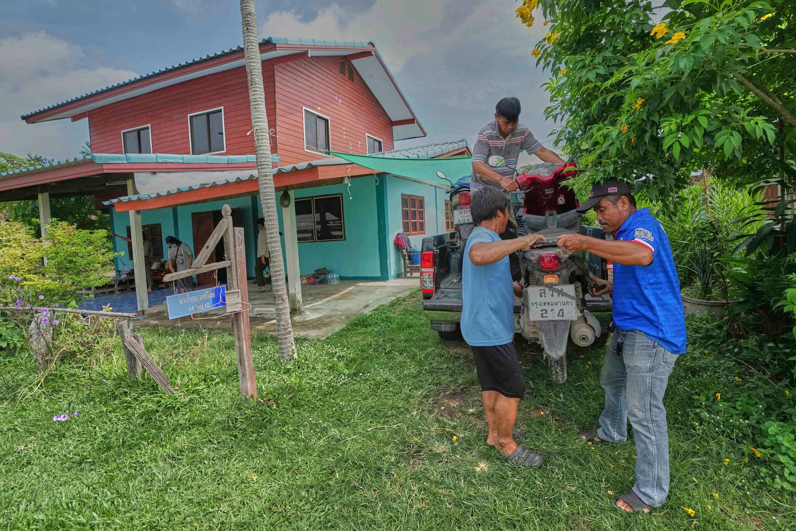 Kritsada Jindasri, top, Sommai Jindasri, left, and Jirayu Jindasri who fled their home following the clashes between Thai and Cambodian soldiers lift a motorcycle off a vehicle as they return home in Surin province, Thailand, Tuesday, July 29, 2025 after the ceasefire was supposed to take effect at midnight on July 28, 2025. (AP Photo/Sakchai Lalit)