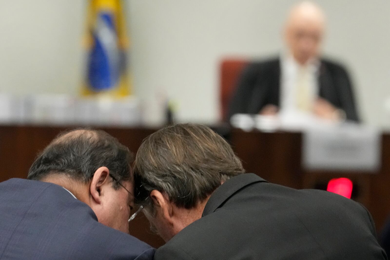 Brazil's former President Jair Bolsonaro, right, talks with his lawyer as he sits before Supreme Court Judge Alexandre de Moraes during his trial, along with others, charged with an alleged coup plot to keep him in office after his 2022 election defeat, in Brasilia, Brazil, Tuesday, June 10, 2025. (AP Photo/Eraldo Peres)