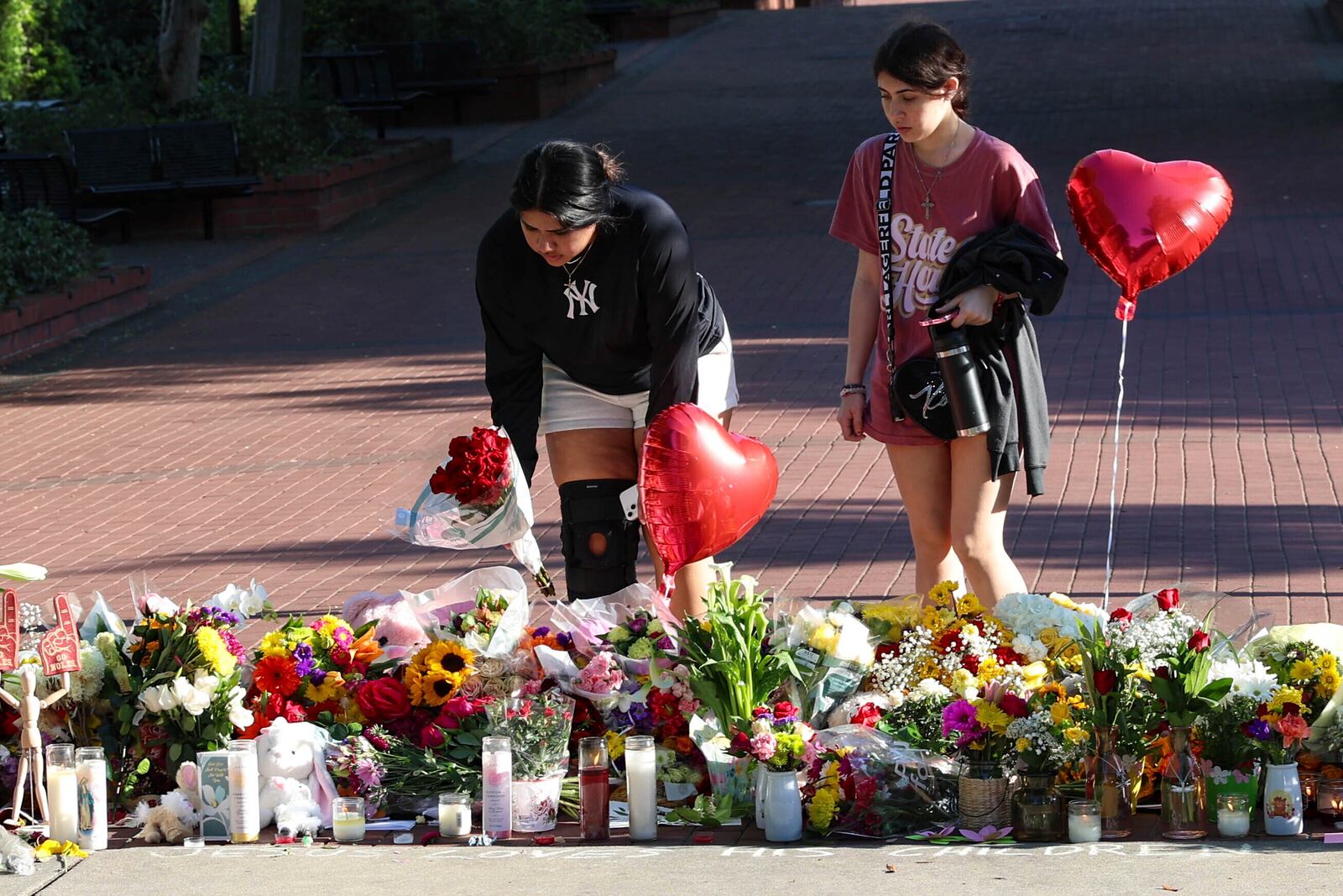 Students place flowers on a stretch of sidewalk near the center of the Florida State campus in sight of the Student Union building, Tallahassee, Fla., Friday, April 18, 2025. (AP Photo/Gary McCullough)