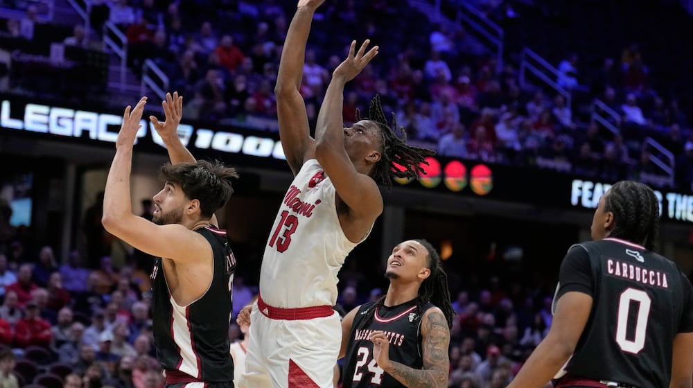 Miami (Ohio) forward Antwone Woolfolk (13) shoots between Massachusetts forward Leonardo Bettiol, left, and guard Marcus Banks (24) in the second half of a basketball game in the quarterfinals of the Mid-American Conference tournament, Thursday, March 12, 2026, in Cleveland. (AP Photo/Sue Ogrocki)