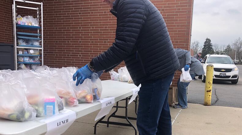 Kettering City Schools employees give out school lunch packages to families in a drive-up service at Fairmont High School on March 24, 2020. JEREMY P. KELLEY / STAFF