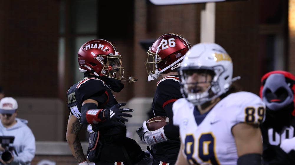 Miami's Eli Coppess (26) celebrates with teammate Kaleb Martin (17) after intercepting a Toledo pass on Wednesday night at Yager Stadium. The RedHawks lost 24-3. ELIJAH COOK / CONTRIBUTED