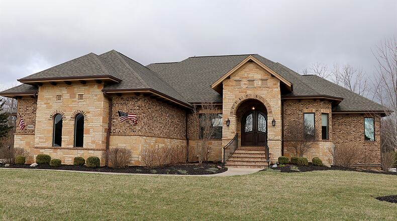 This Tuscan-inspired stone ranch with 4 bedrooms and about 6,120 sq. ft. of living space sits on an acre-plus property with a tree-lined back yard that is surrounded by a wrought-iron fence. There is a 2-bay, 3-car garage and a finished lower level. CONTRIBUTED PHOTO BY KATHY TYLER