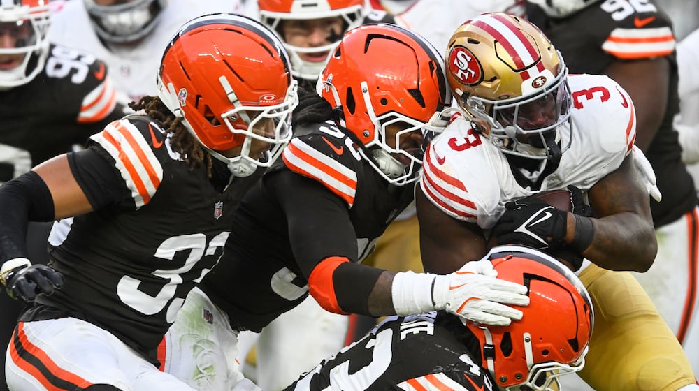 San Francisco 49ers running back Brian Robinson Jr. (3) runs against Cleveland Browns safety Ronnie Hickman Jr. (33), linebacker Devin Bush, middle, and linebacker Mohamoud Diabate, bottom, during the second half of an NFL football game, Sunday, Nov. 30, 2025, in Cleveland. (AP Photo/David Richard)