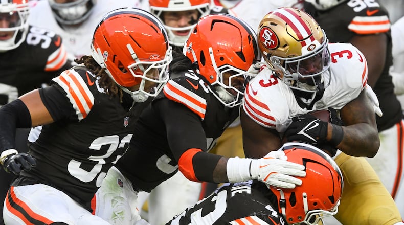San Francisco 49ers running back Brian Robinson Jr. (3) runs against Cleveland Browns safety Ronnie Hickman Jr. (33), linebacker Devin Bush, middle, and linebacker Mohamoud Diabate, bottom, during the second half of an NFL football game, Sunday, Nov. 30, 2025, in Cleveland. (AP Photo/David Richard)