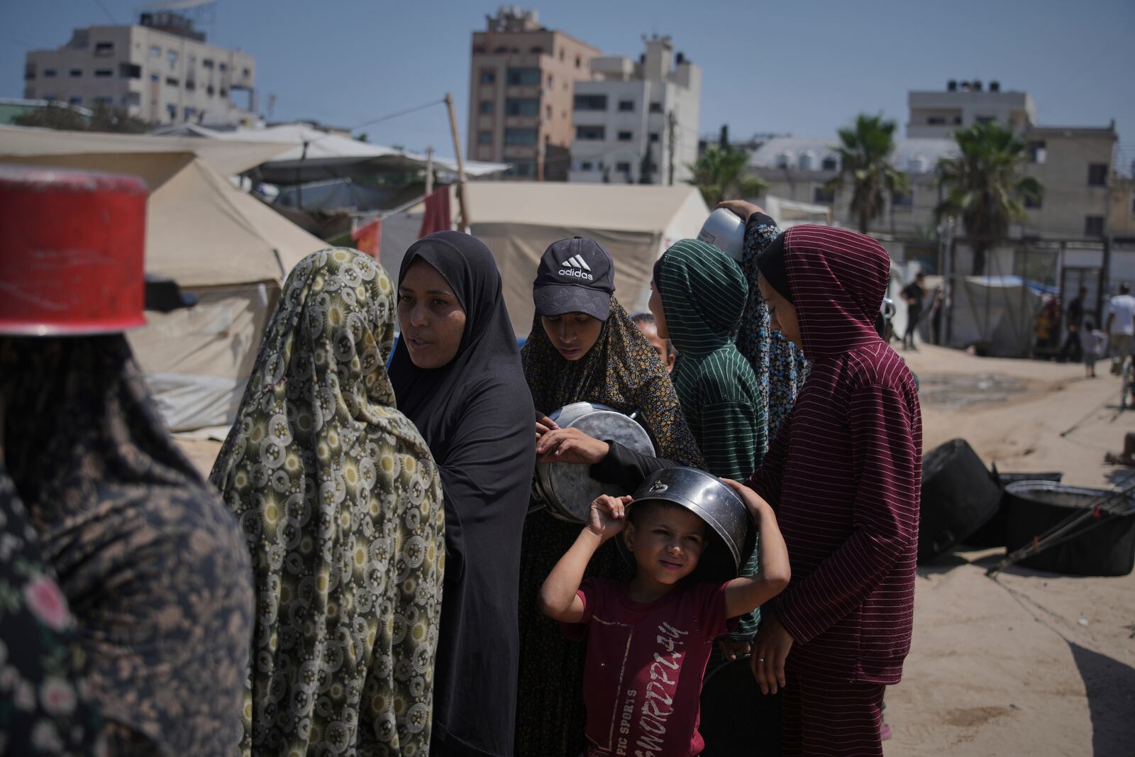 Displaced Palestinians wait for donated food at a community kitchen in Gaza City, northern Gaza Strip, Tuesday, July 22, 2025. (AP Photo/Jehad Alshrafi)