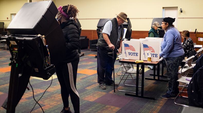 Carshena Williams, 40, of West Toledo, votes while Terry and Diane Shankland vote via a paper ballots provided by poll workers Marie Salazar and Francine Nash at the Kent Branch Library Polling location in Toledo, Ohio, on Tuesday May 3, 2022. (Stephen Zenner/The Blade via AP)