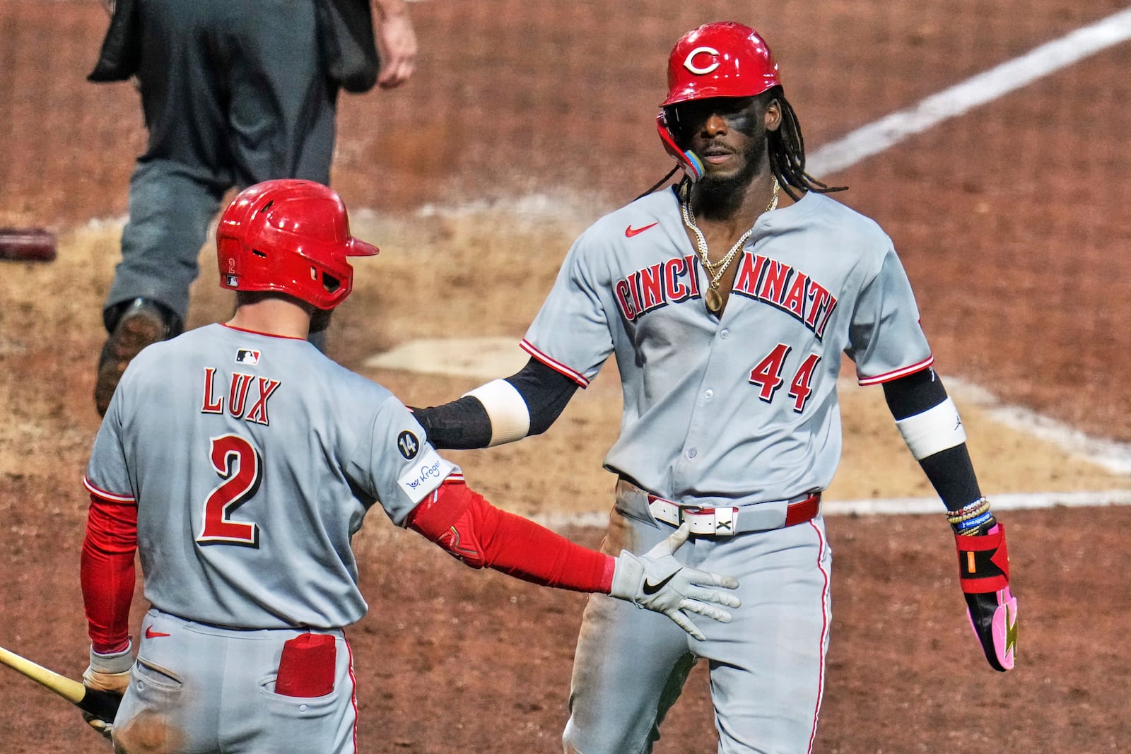 Cincinnati Reds' Elly De La Cruz (44) is greeted by Gavin Lux as he returns to the dugout after scoring from third on a single by Austin Hays off Pittsburgh Pirates pitcher David Bednar during the eighth inning of a baseball game in Pittsburgh, Monday, May 19, 2025. (AP Photo/Gene J. Puskar)