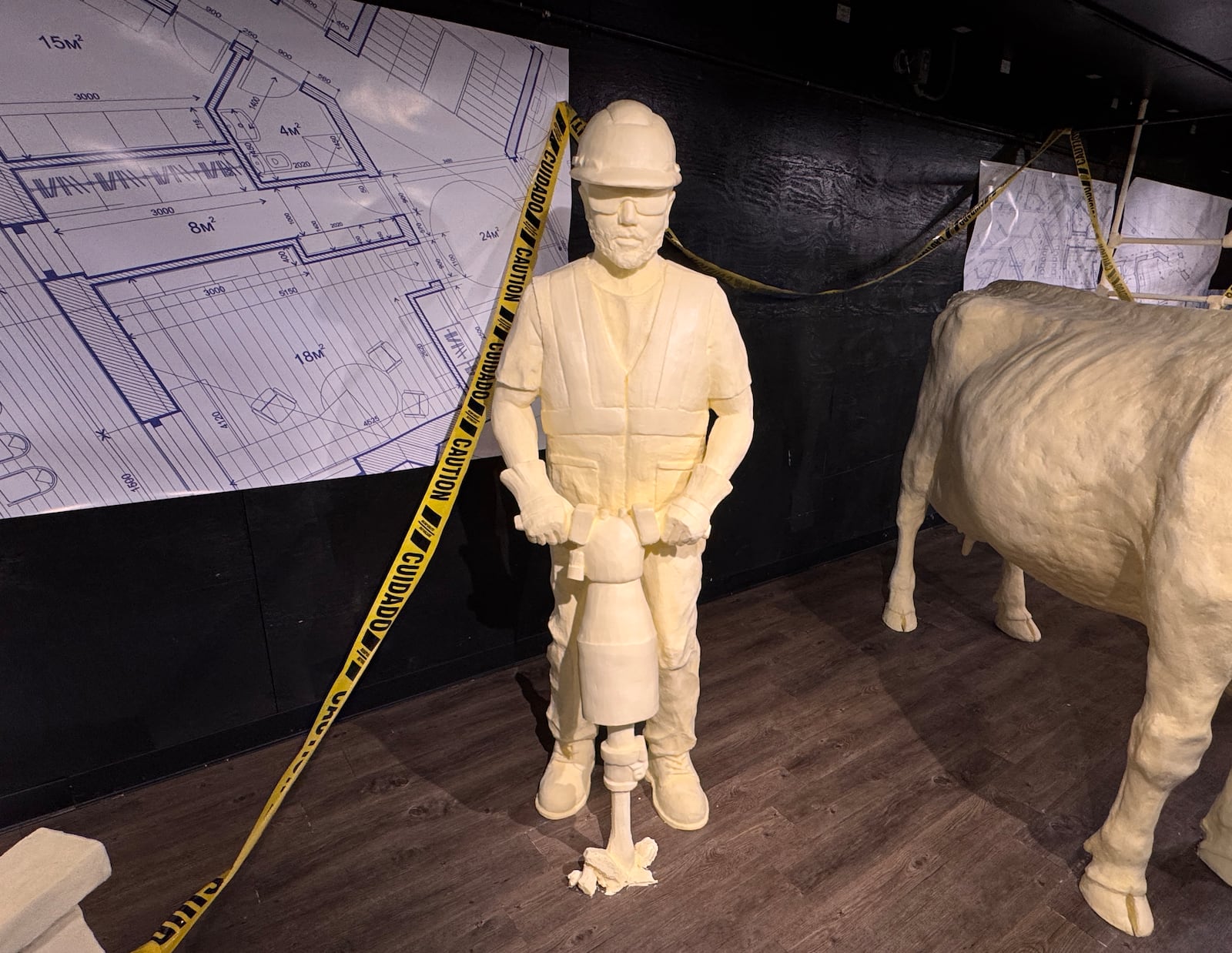 A butter construction worker operates a jackhammer as part of the 2025 butter cow display at the Ohio State Fair.