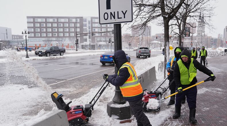 Workers clear snow off the ground Sunday, March 15, 2026, in St. Paul, Minn. (AP Photo/Abbie Parr)