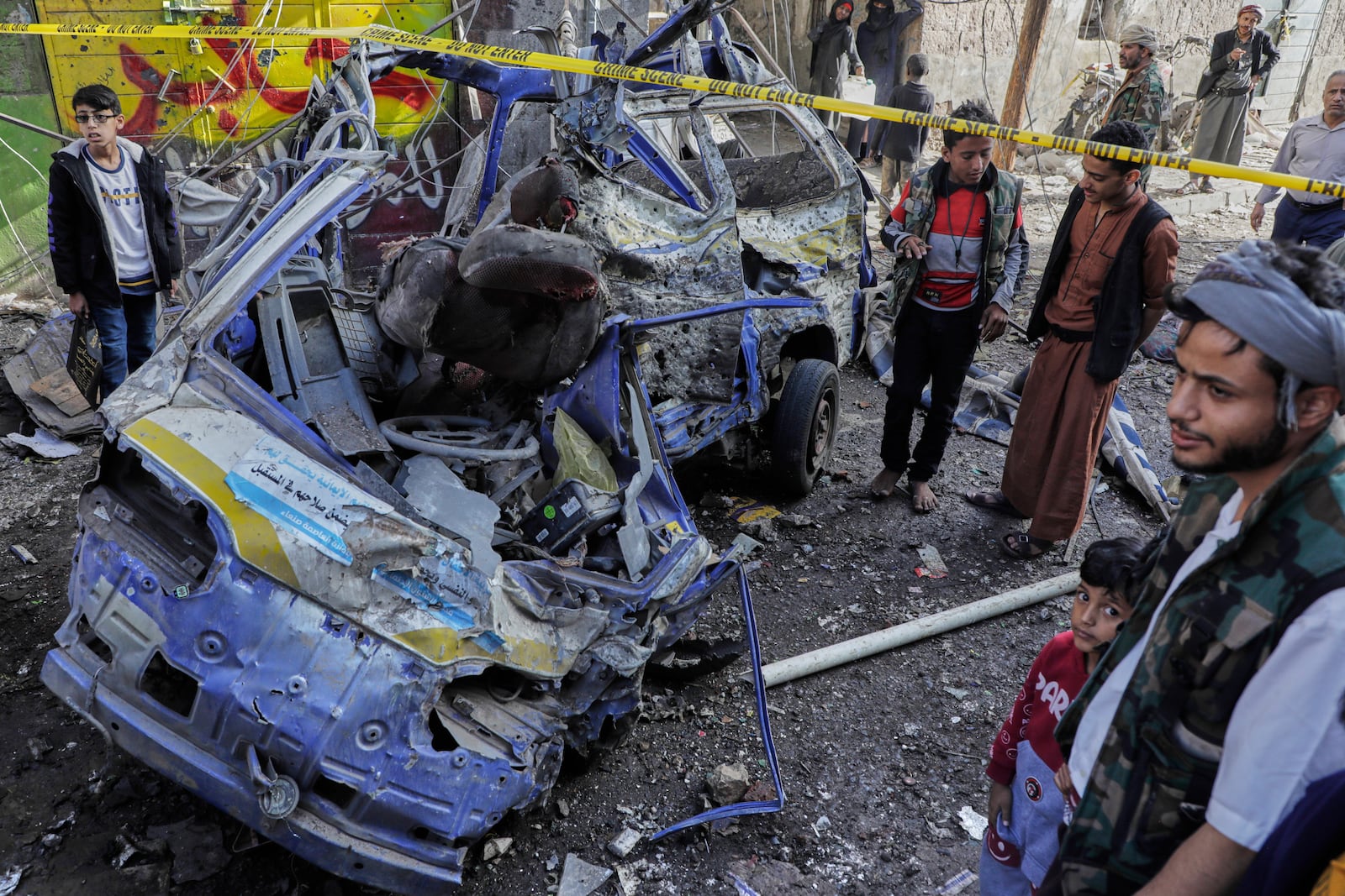 Yemenis watch a damaged vehicle at Farwah popular market which Houthis said it was struck by U.S. airstrikes in Sanaa, Yemen, Monday, April 21, 2025. (AP Photo)