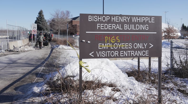FILE - Protesters yell at cars coming and going near a defaced sign for Bishop Whipple Federal building in Minneapolis on Wednesday, Jan. 28, 2026. (AP Photo/Laura Bargfeld, File)