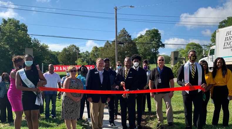 Xenia Mayor Sarah Mays, Greene County Commissioner Dick Gould, and Xenia Township Administrator Alan Stock join Wilberforce president Elfred Anthony Pinkard in cutting the ribbon on a new sidewalk at the university.
