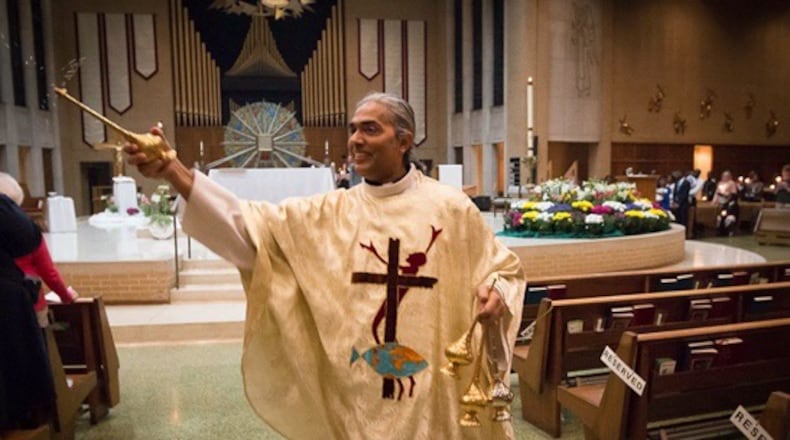 Father Satish sprinkles holy water on the congregation at mass at Immaculate Conception. The fancy sprinklers are gifts from his mom and late father in India. CONTRIBUTED