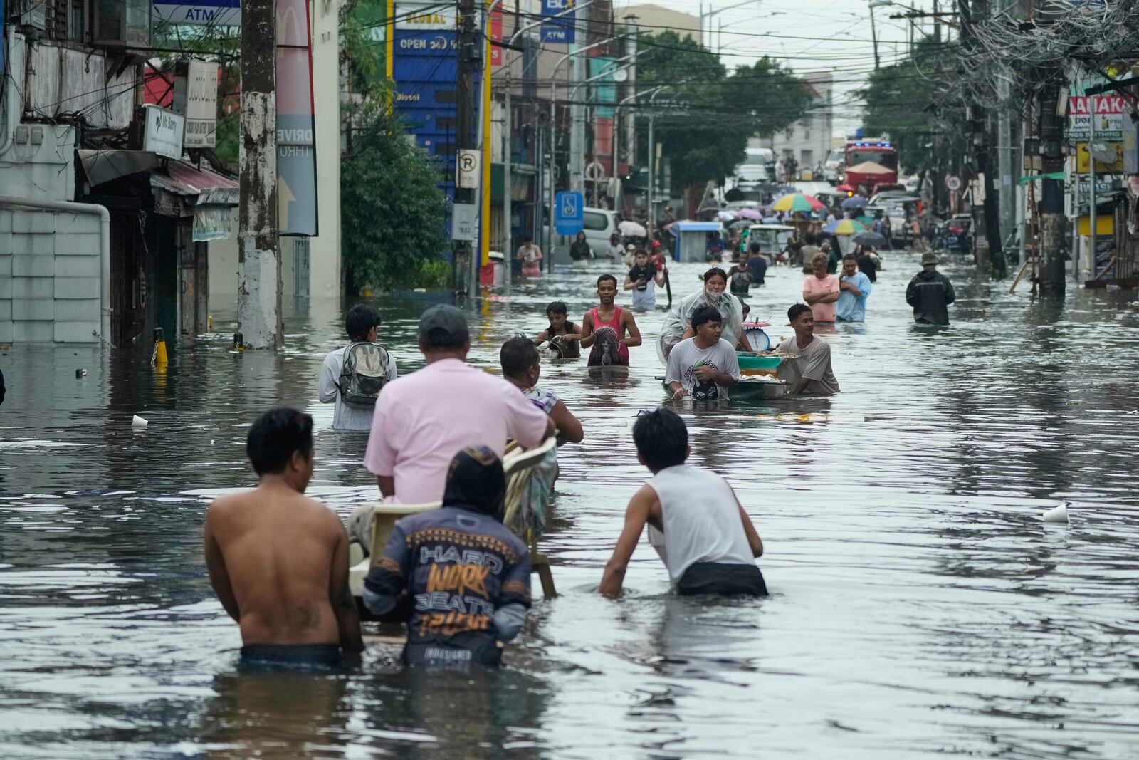 Residents wade along a flooded road as Typhoon Co-may intensified seasonal monsoon rains at Malabon city, Philippines on Friday, July 25, 2025. (AP Photo/Aaron Favila)