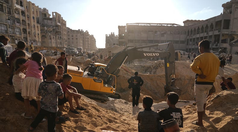 Palestinians watch machinery and some workers from Egypt searching for the bodies of hostages at Hamad City, in Khan Younis, southern Gaza Strip, Sunday, Oct. 26, 2025. (AP Photo/Jehad Alshrafi)